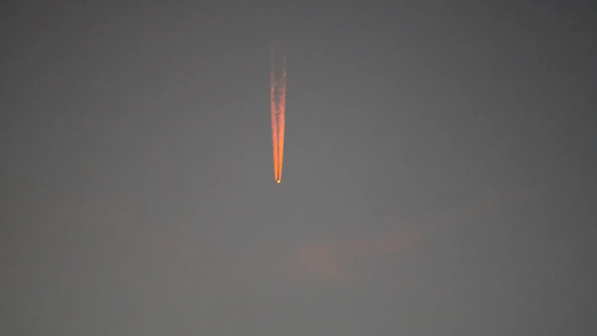Ballistic missile launching with white exhaust trail against blue sky